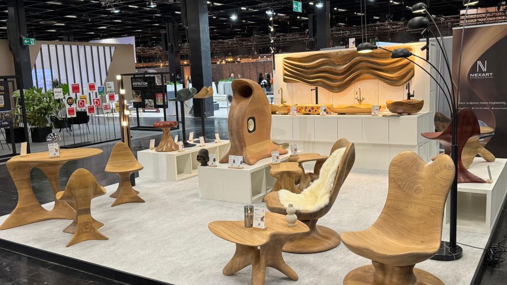 NEXART-beursstand met sculpturale houten meubels, wastafels, wandkunst en een luidspreker