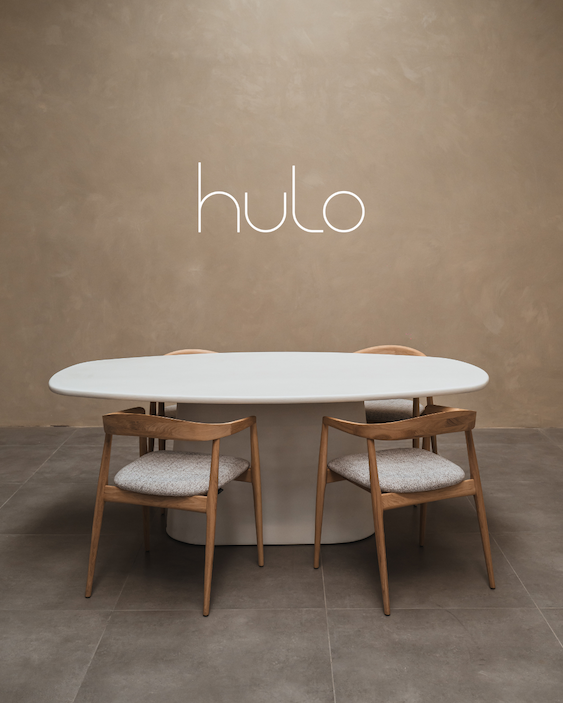 Tafel gemaakt in steenkool. tafelblad heeft de vorm van Deens Ovaal en het onderstel is een piramidevorm. Houten stoelen staan rond de tafel. Tafel is gefotografeerd in fotostudio.