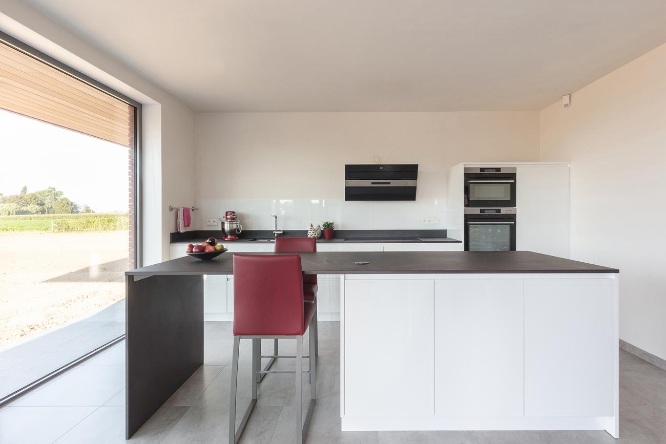 Greeploze keuken in witte hoogglanslak met Dekton werkblad.