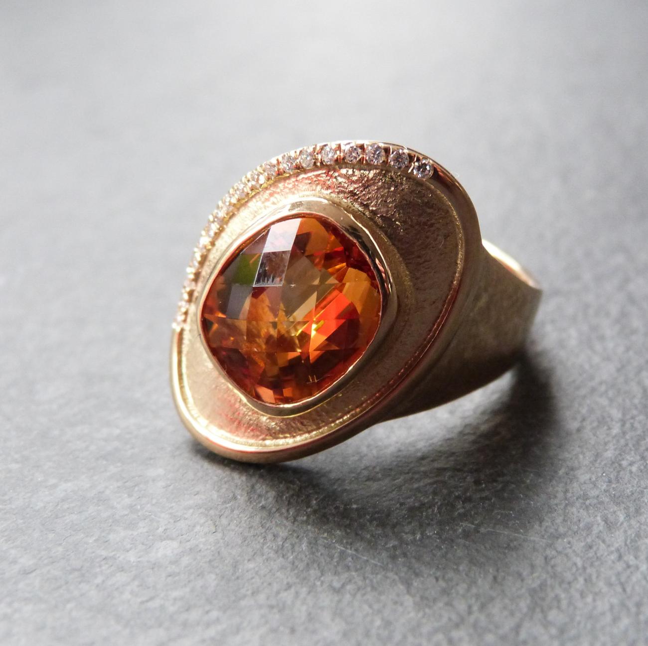 Voor dit ontwerp kregen we zo goed als carte blanche. Voor de klant waren de grote Citrien, de diamantjes en het oud Goud van emotioneel belang. Dat moest de basis zijn van een nieuwe ring en het moest een makkelijk draagbare ring worden. De Citrien is geplaatst in een kastzetting, het geheel licht ietwat schuin op de vinger. Op een deel van de rand zie je een kasteelzetting van een 25-tal eigen diamanten. Geel Goud – Citrien – Diamanten