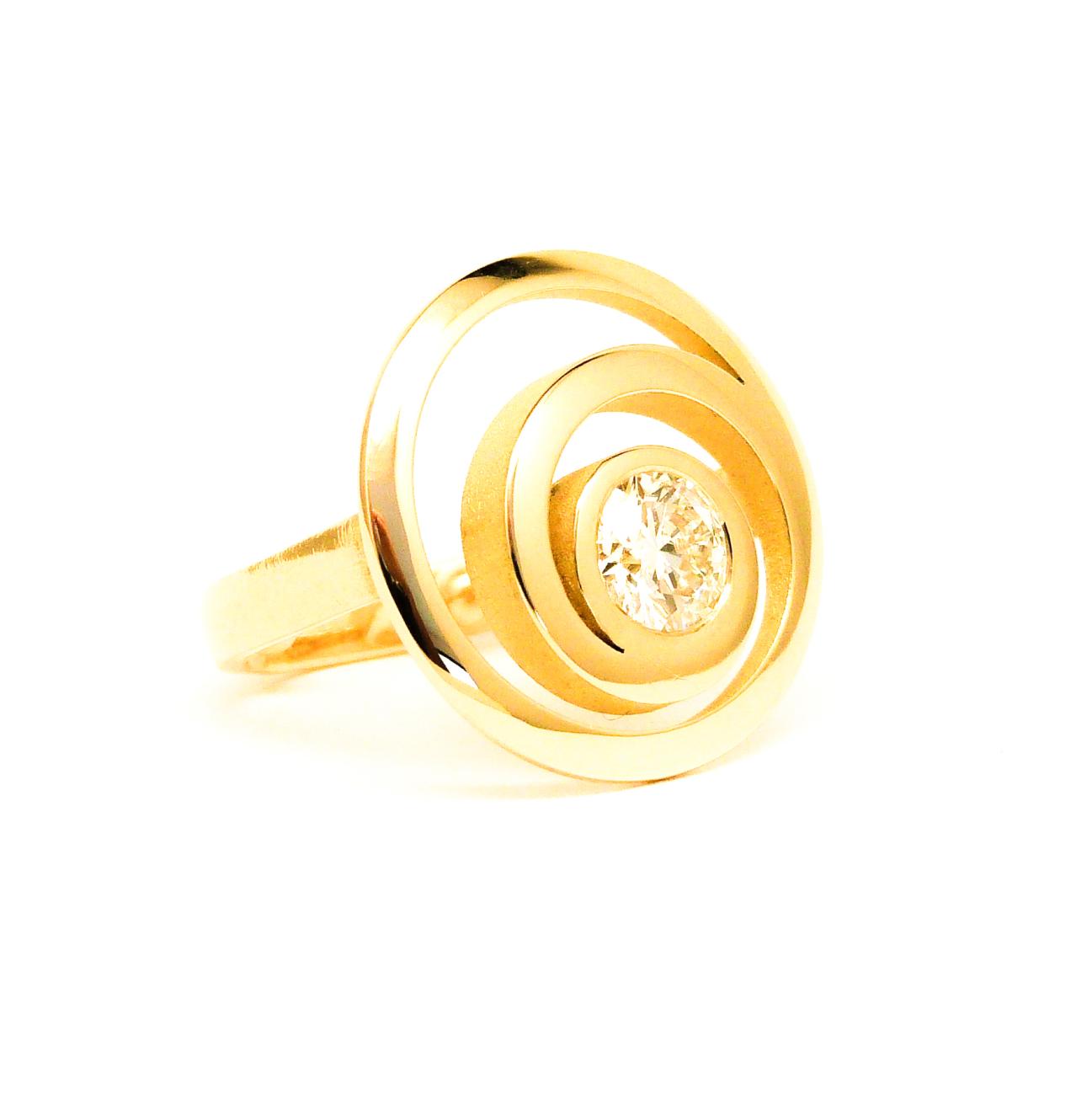 De diamant (1 karaat) was beladen met emoties uit het verleden. Door een sjamanistisch heeling werd de diamant gezuiverd. Hij staat voor een nieuw begin en vormt tevens de verbinding tussen heden en verleden. De steen is gezet in een naar 2 richtingen draaiend spiraal. Zo wordt het verleden meegenomen naar het heden om een mooie toekomst te kennen, zonder spijt over vroeger. Geel Goud – Diamant 1kt.