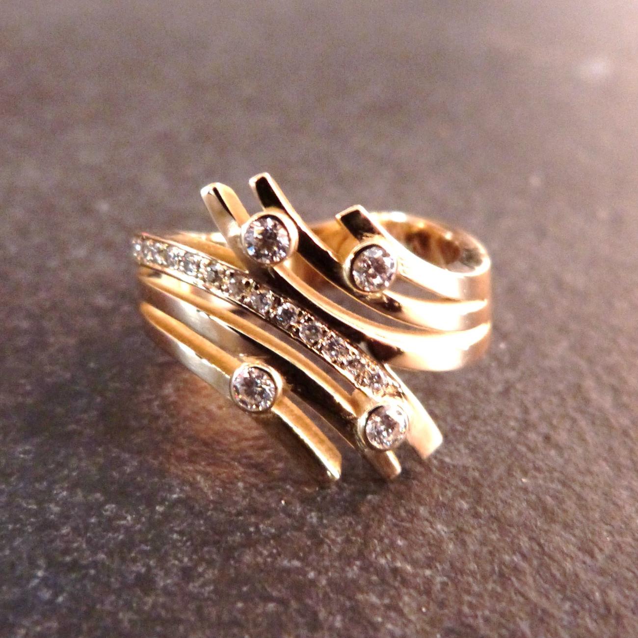 Deze ring is ontworpen met als basis de diamanten van de klant die voor haar een emotionele lading hebben. De ring splitst naar boven toe in 6 banden, 3 aan elke zijde. Het lijken wel 2 regenbogen tegenover elkaar. Zij koos ervoor om 4 grote diamanten te gebruiken in het ontwerp en 12 kleinere. De cijfers 4 en 12 zijn voor haar belangrijke elementen waar we de betekenis niet van kennen. Deze 4 grote diamanten werden in een kastzetting geplaatst en maken elk op hun beurt de verbinding tuss