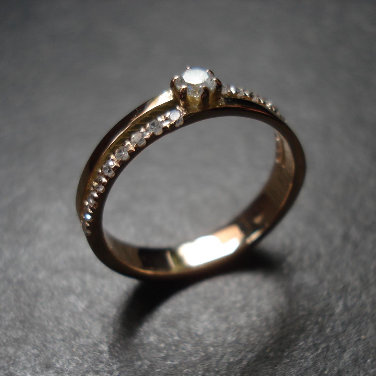 De diamanten en oud goud van de klant zijn de items voor het ontwerpen van deze ring De ring is opgebouwd uit 2 ringen, één in Rosé Goud en de andere in Geel Goud.  De grotere diamant houdt de twee ringen bovenaan samen. Elk van de twee ringen heeft een kasteelzetting van 9 diamantjes.  