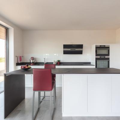 Greeploze keuken in witte hoogglanslak met Dekton werkblad.