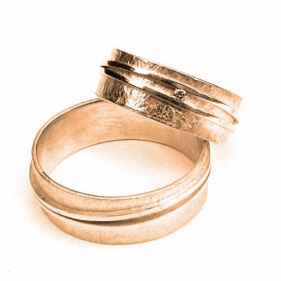 Twee strakke bandjes die een vloeiende beweging maken rondom de met de hamer bewerkte ringen  Met voor haar heel subtiel een diamantje. Palladium Wit Goud - Diamant